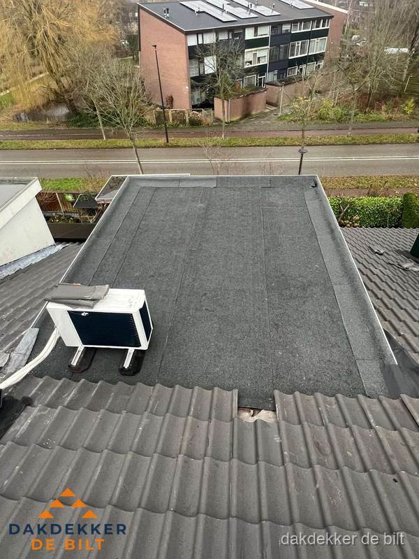 Plat dak inspectie met bitumen bedekking naast schuin pannendak in De Bilt