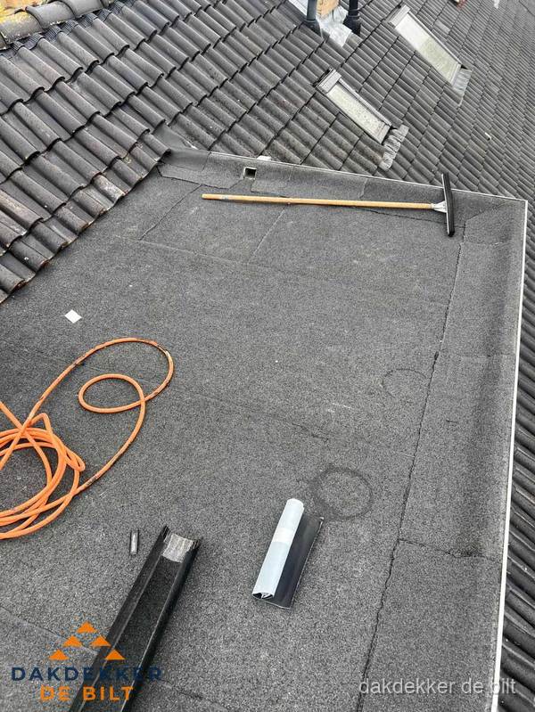 Plat dak reparatie met gereedschap en loodstroken in De Bilt