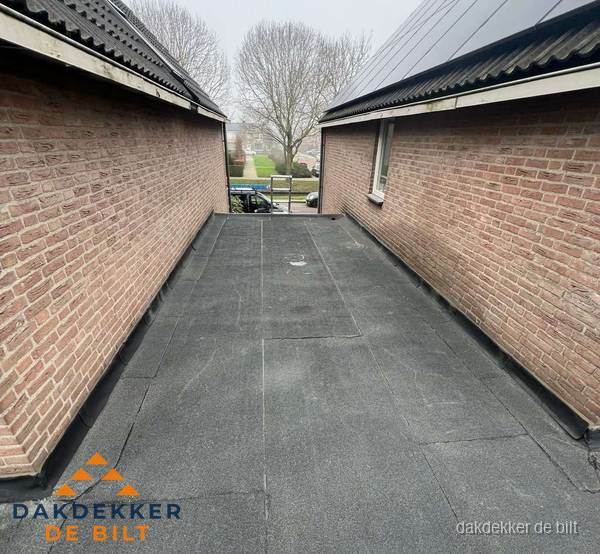 Plat dak met bitumen dakbedekking tussen bakstenen muren in De Bilt
