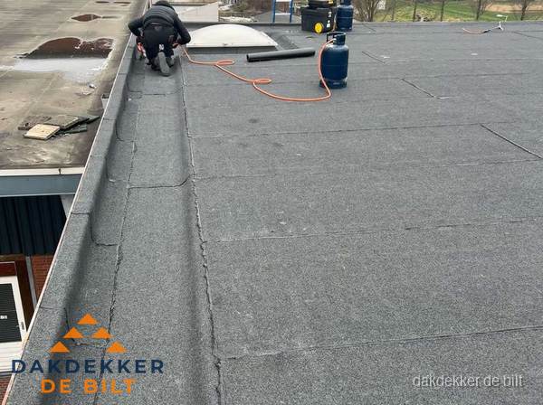 Dakdekker repareert bitumen dakbedekking op groot plat dak in De Bilt