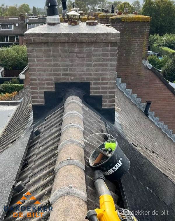 Schoorsteen met loodaansluiting en nokvorst op pannendak in De Bilt