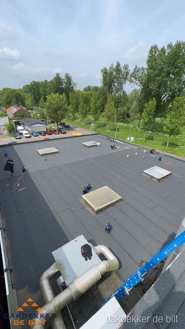 Dakdekker aan het werk op groot plat dak met bitumen in De Bilt